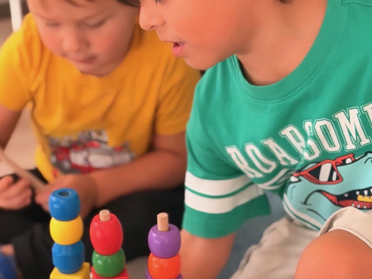 Children stacking colorful wooden rings