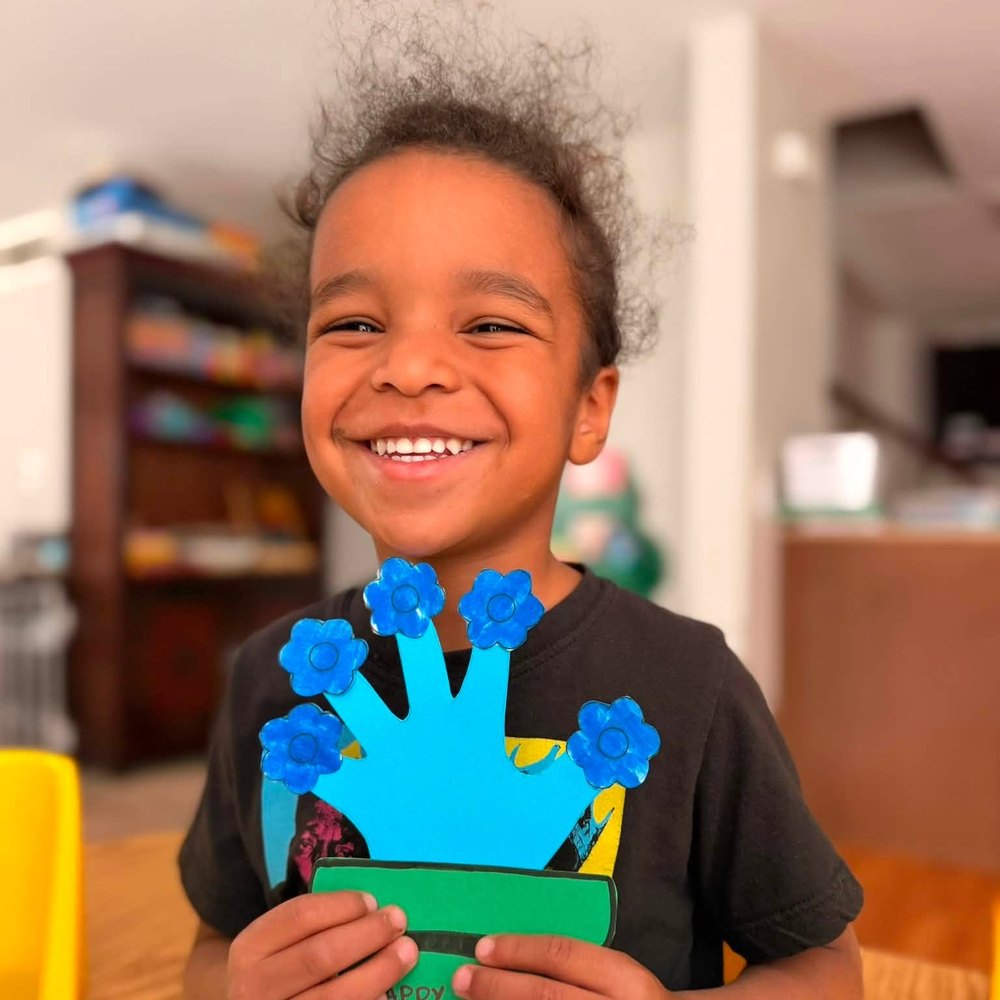 Smiling student presenting a handprint craft project