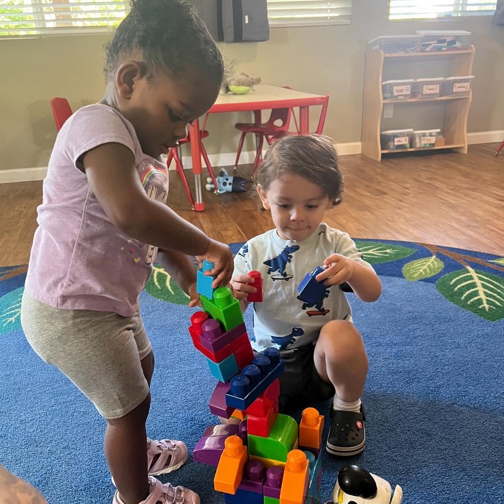 Children building a tall tower with wooden blocks