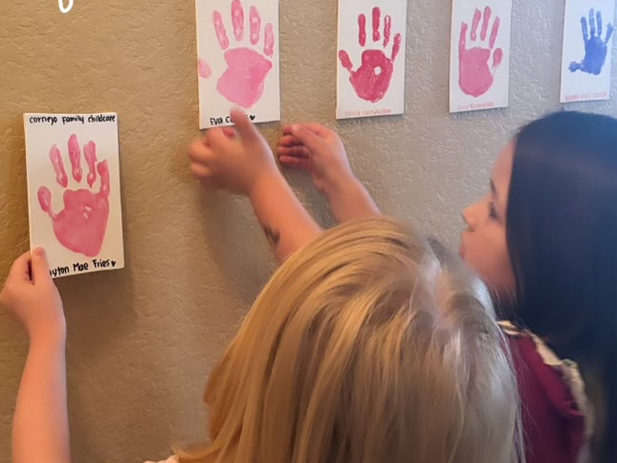 Pre-K children adding handprints to a classroom wall