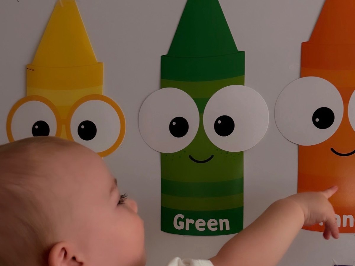 A child pointing out colors on the crayon wall