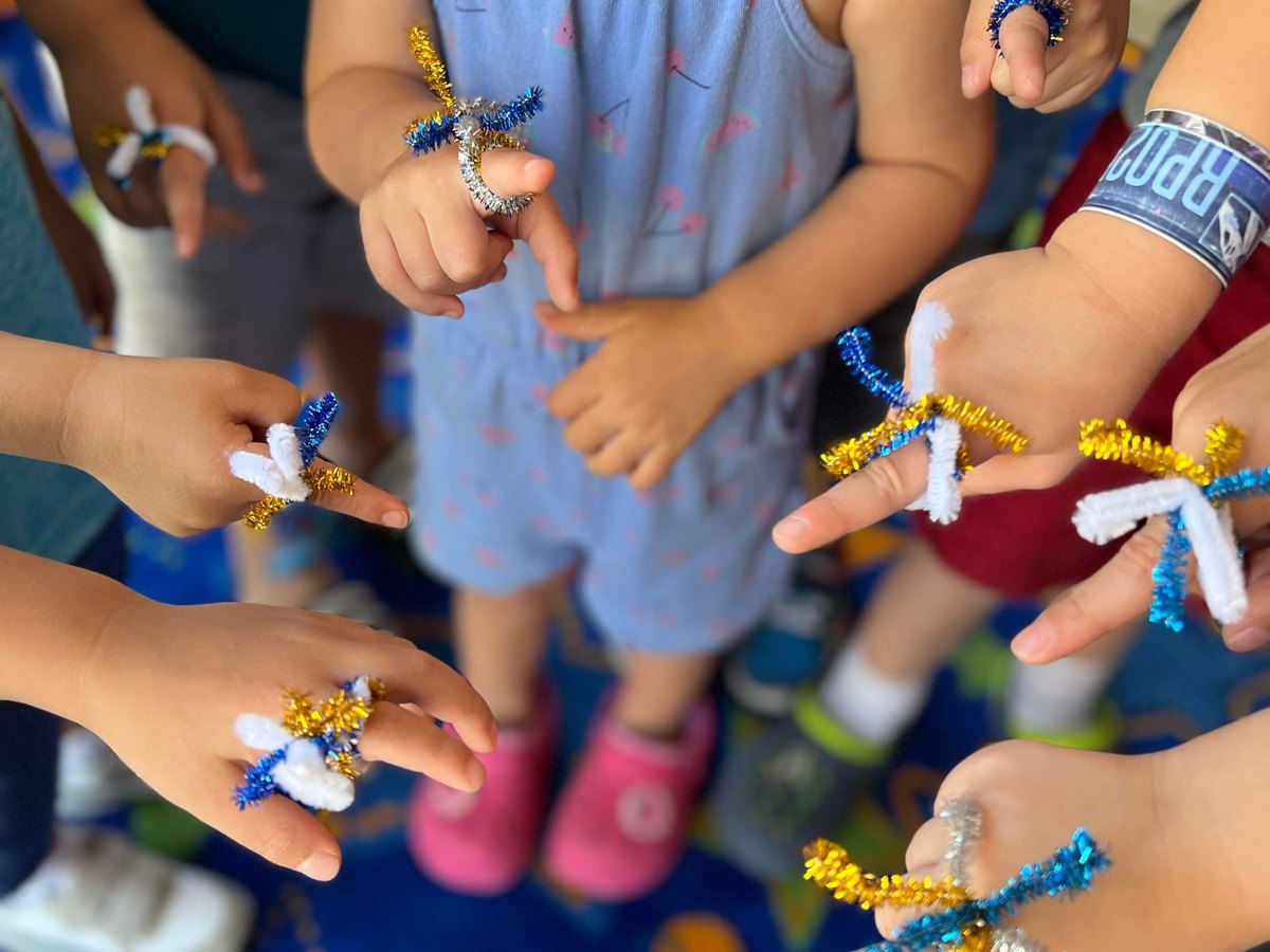 Pre-K children holding pipe-cleaner crafts