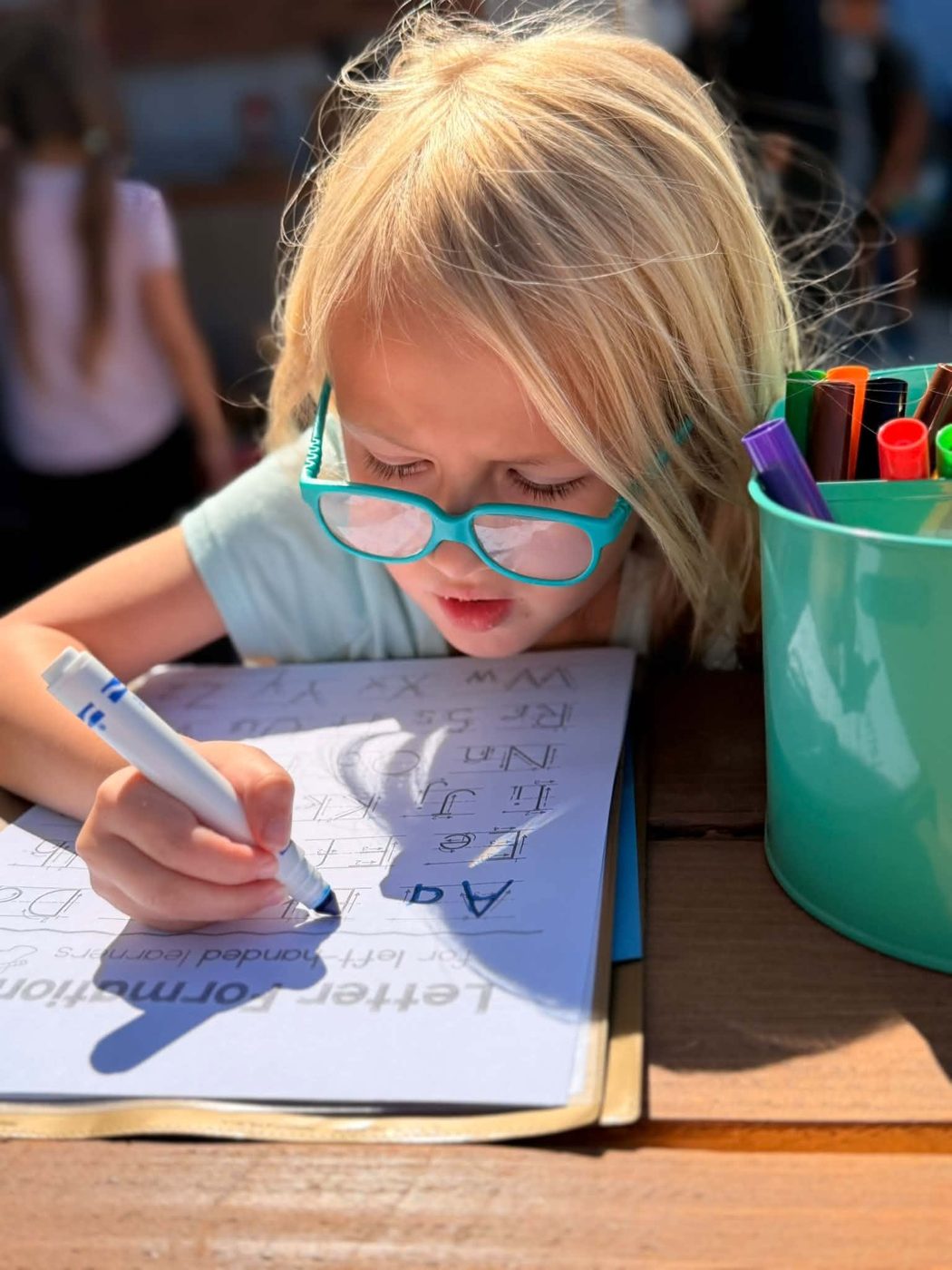 Student practicing writing at a classroom table