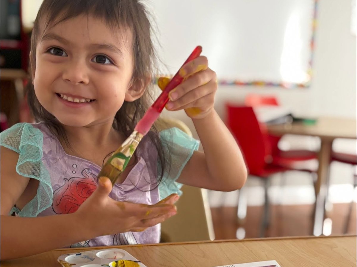 Pre-K child arranging letter tiles at a sunlit table